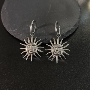 Silver sun face drop earrings in 18K gold plated titanium steel on a dark stone