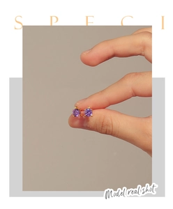 Detailed macro view of turtle stud earrings with purple zircon stones and gold plating