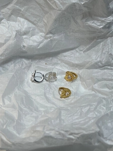 Detail of silver and gold heart huggie earrings with radiant texture and zircon centers