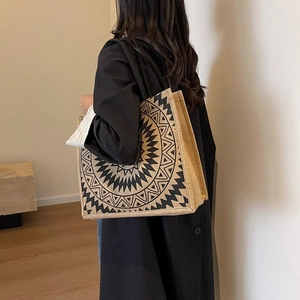 Detail of large linen tote bag featuring a black mandala pattern worn by a model
