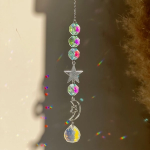 Close-up of crystal prism suncatcher reflecting rainbow light with silver moon and star charms