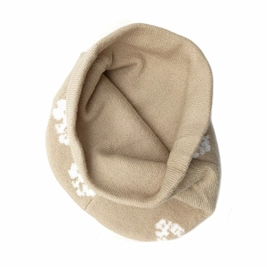 Detail of beige knit beanie showing white floral jacquard pattern and ribbed texture