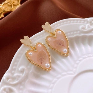Macro shot of gold plated heart earrings with resin fill and micro pearl details