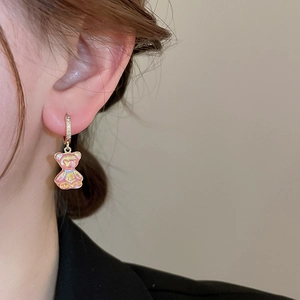 Gros plan d'une boucle d'oreille ours en résine rose avec anneau doré serti de zircons