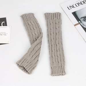 Detail view of grey cable knit fingerless gloves on a minimalist white background