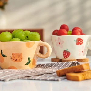 Detail of hand-painted ceramic mugs featuring cute tiger and strawberry designs