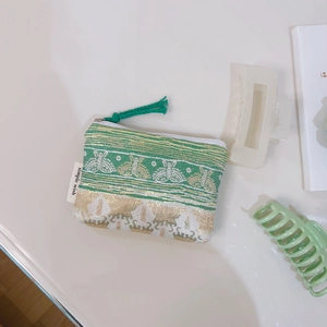 Macro detail of green floral jacquard coin purse with gold patterns and zipper closure
