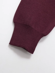 Close-up detail of burgundy knit sweater showing ribbed cuffs and fine textile texture