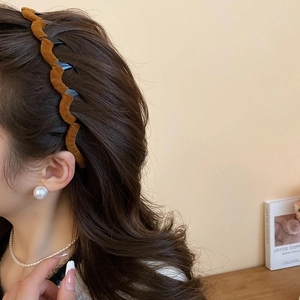 Detail view of brown velvet wavy headband worn on hair, showing soft texture and retro style