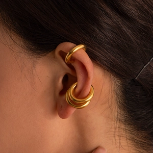 Detailed close-up of polished gold-finished minimalist stainless steel ear cuffs on ear