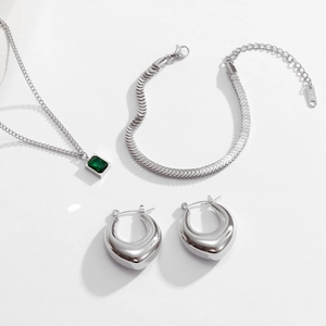 Macro detail of silver jewelry set with emerald zircon stones and fish scale link chain