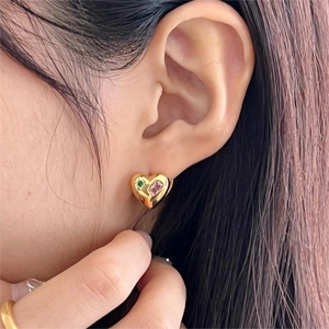 Golden heart earrings with pink and green stones worn on ear for minimalist fashion style