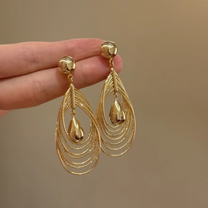 18k gold plated multi-layer hollow teardrop earrings held by hand for scale