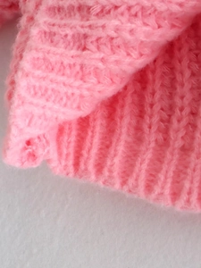 Dettaglio ravvicinato di maglione rosa in maglia con trama a coste e filato morbido