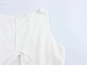 Close-up of white V-neck dress with hidden zipper and delicate lace-up neck detail