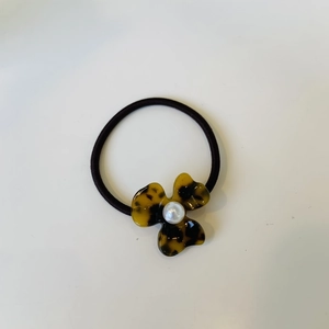 Macro detail of elastic hair tie with amber leopard petals and pearl centerpiece
