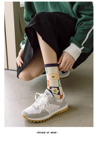 Close-up of knit crew socks with retro checkerboard pattern and yellow sun flower icons