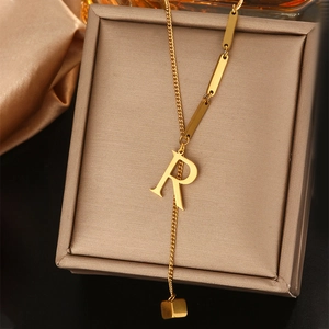 Detail macro-opname van gouden letter R-hanger en vierkante bedel aan de halsketting