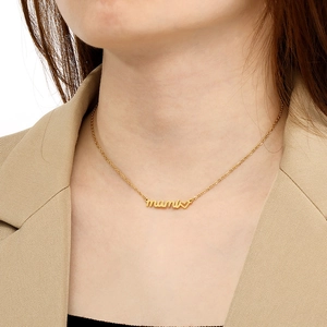 Close-up of golden MAMA pendant necklace with heart detail worn on a model neckline