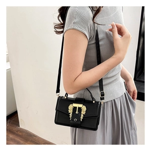 Detail shot of black leather square bag featuring a gold baroque lion head buckle