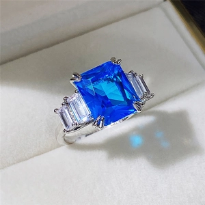 Macro view of blue emerald-cut zircon cocktail ring with side stones in velvet box