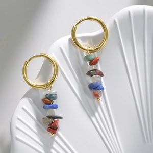 Detail of 14k gold earrings with colorful natural stones on a white shell display