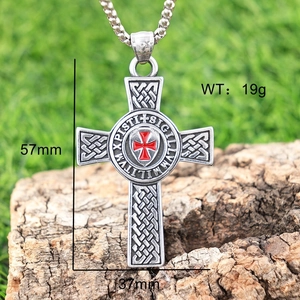 Detailed view of silver Celtic cross pendant with red enamel on natural bark background