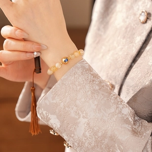 Detail of yellow citrine bead bracelet with gold lucky bead worn with traditional attire