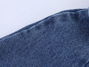 Close-up of premium blue denim fabric showing high-density texture and precise stitching