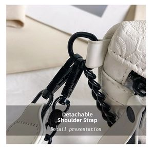 Close-up of white embossed floral crossbody bag with matte black metal chain and lobster clasp