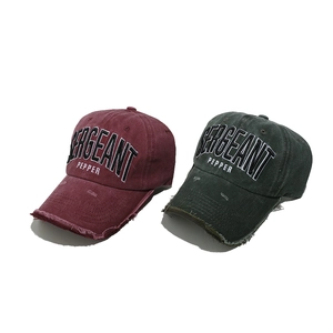 Close-up of distressed cotton baseball caps with vintage embroidery and frayed brim details