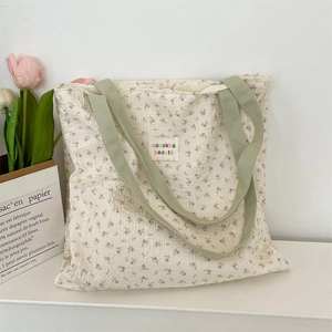 Detail of floral canvas tote bag with textured bubble fabric and green straps
