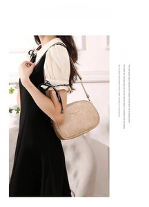Detail of beige textured leather shoulder bag featuring golden Sunnyside logo and metal buckle