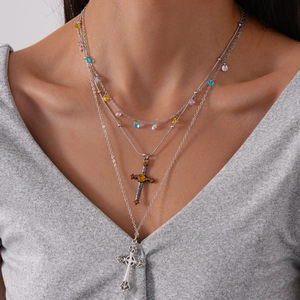 Close-up of multilayered silver cross necklace with colorful beads on a model's neck