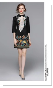 Detailed close-up of colorful floral embroidery and bow tie on a black midi dress