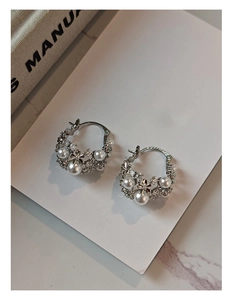 Detail view of silver floral hoop earrings with pearls and cubic zirconia on marble