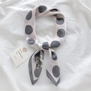Detail of grey polka dot silk scarf tied with vintage camera print on white fabric