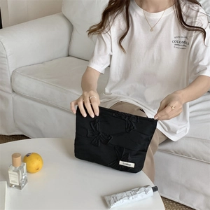 Detail of black quilted butterfly cosmetic bag with a zipper and embroidered texture