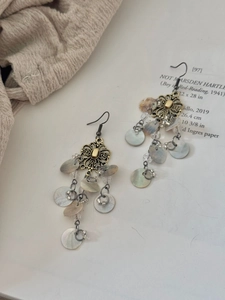 Detail of vintage bronze flower earrings with shell tassels and dangling metal chains