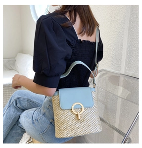 Detail of light blue leather and straw bucket bag with gold circular metal buckle