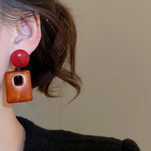 Close-up of vintage acrylic square drop earrings with red studs on model's ear