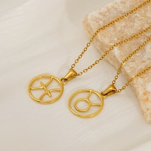 Detail of golden zodiac necklaces with Pisces and Taurus pendants on a textured stone base
