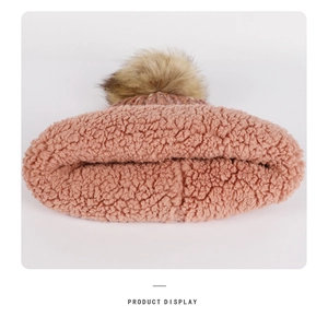 Detail of pink knit hat showing soft fleece lining and fluffy brown pompom decoration