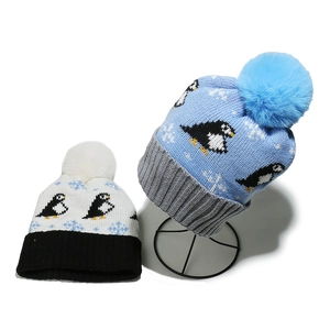Knitted winter beanie with cute penguin jacquard, fluffy pompom and warm ribbed cuffs