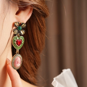 Gros plan de boucles d'oreilles vintage avec émail cœur vert et portrait camée rose