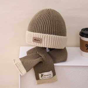 Close-up of olive green and beige ribbed knit winter hat and scarf set with leather label