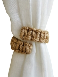 Detail of handcrafted bohemian cotton rope tieback with natural twisted texture on white curtain