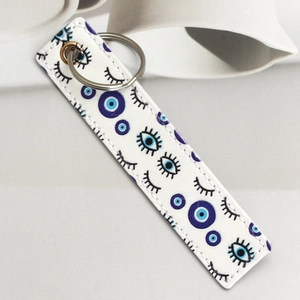 Detail of white PU leather keychain with blue evil eye print and fine stitching