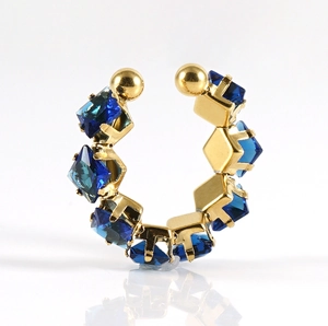 Macro-opname van een 18k gouden oormanchet met vierkante blauwe kristallen op spiegel