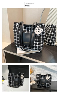 Detail of checkered tote bag with leather pocket and cartoon cat pendant